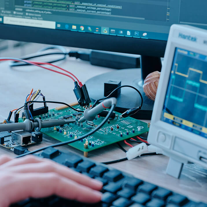 A PCB lying on a table and connected to measuring equipment through wires.