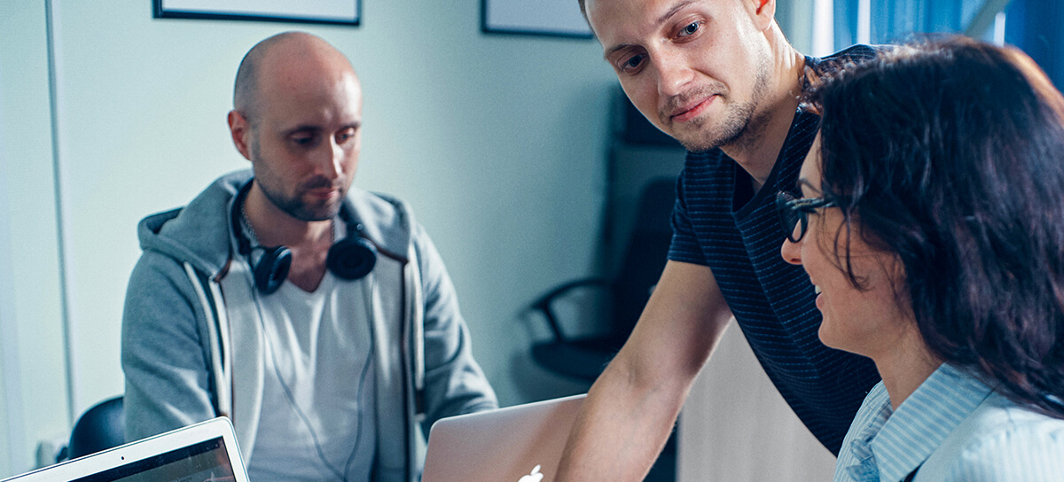 MainImage_1200x544 Two men and one woman are discussing work at a desk