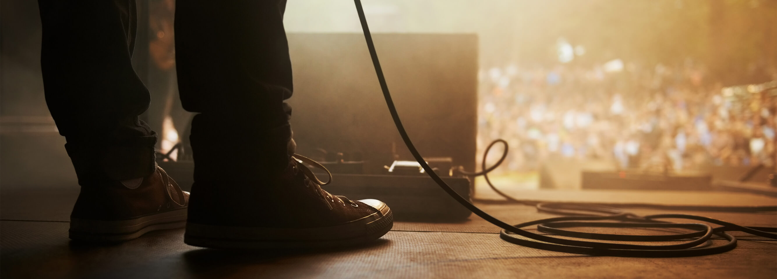 A man standing on a stage in front of a music pedal case.