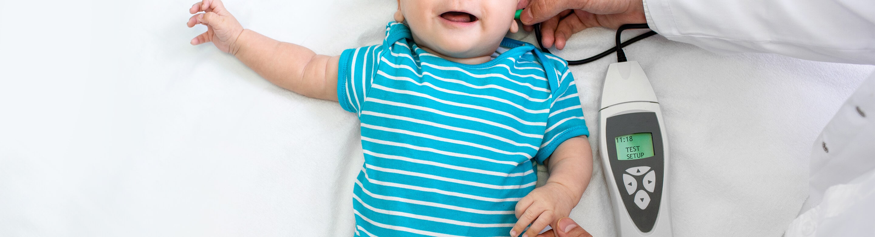 A doctor is conducting a hearing test for an infant using a portable electronic device.