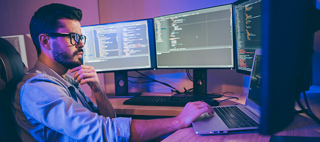 Two Dell monitors, a keyboard, and a cup on a table.