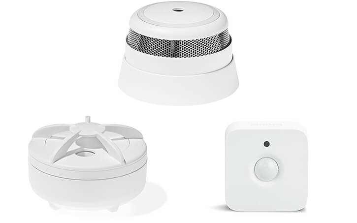 A collage of smart home sensors: a motion sensor from Philips, a smoke alarm, and a water leak detector from Develco.