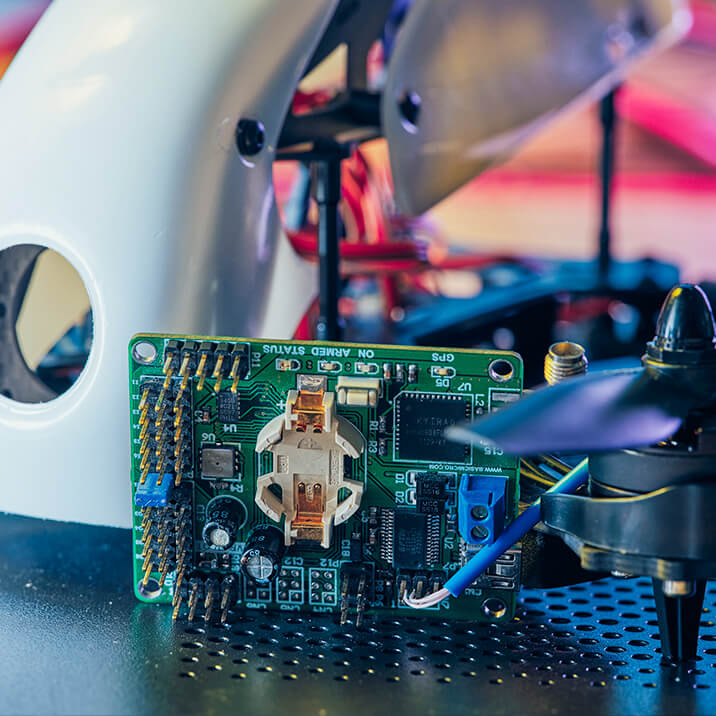 An autopilot PCB and an airscrew lying near a drone enclosure