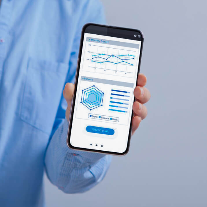 A man holds a smartphone with a data analytics app on the screen.