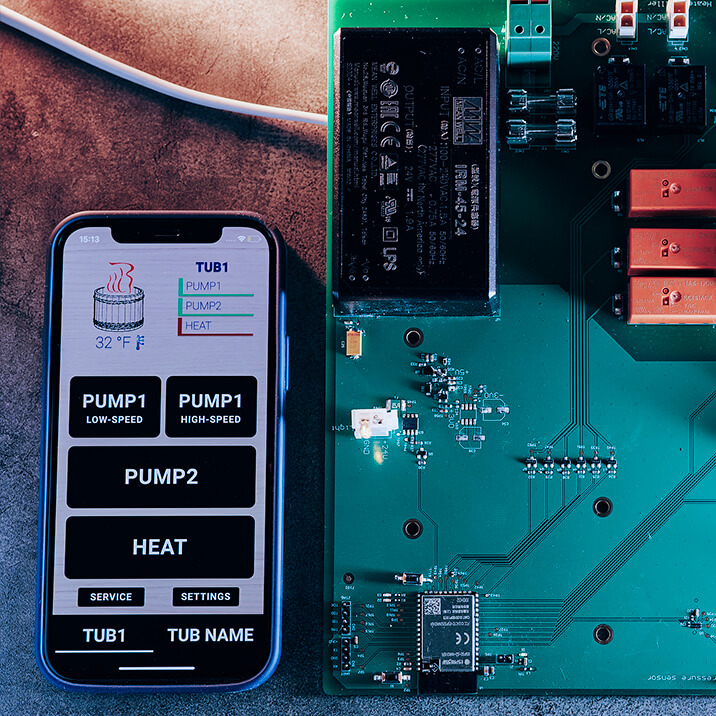 A smartphone with a mobile app launched on it and a PCB lying on a table.