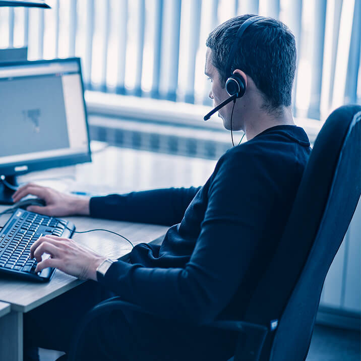 A customer service specialist is answering the phone sitting at his desk.