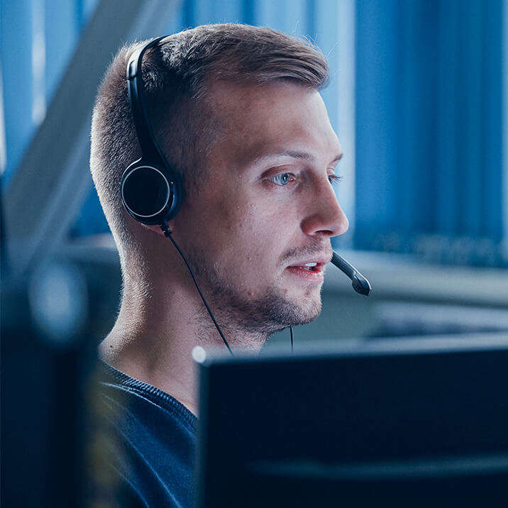 A customer service specialist is talking on the phone at his desk.