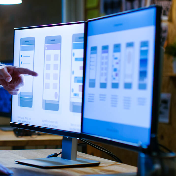 Two monitors with a mobile app UI/UX design sketch