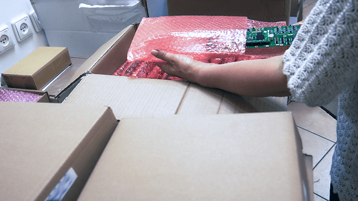 A woman is taking out a PCBA wrapped in anti-static bubble wrap from a box.
